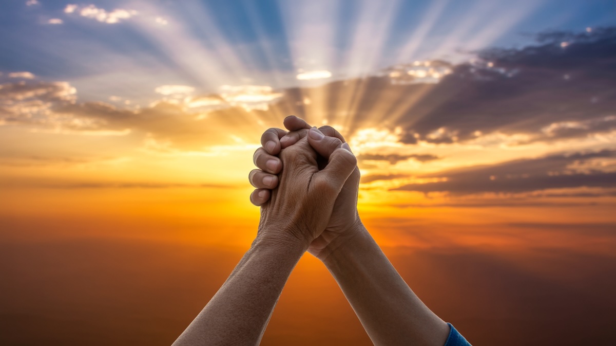 Hands raised in prayer for help and guidance with beautiful sunrise representing God's divine direction and wisdom