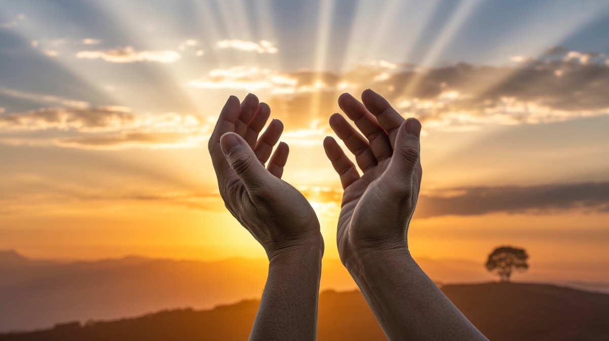 Person praying for help and guidance during peaceful morning devotion with sunrise